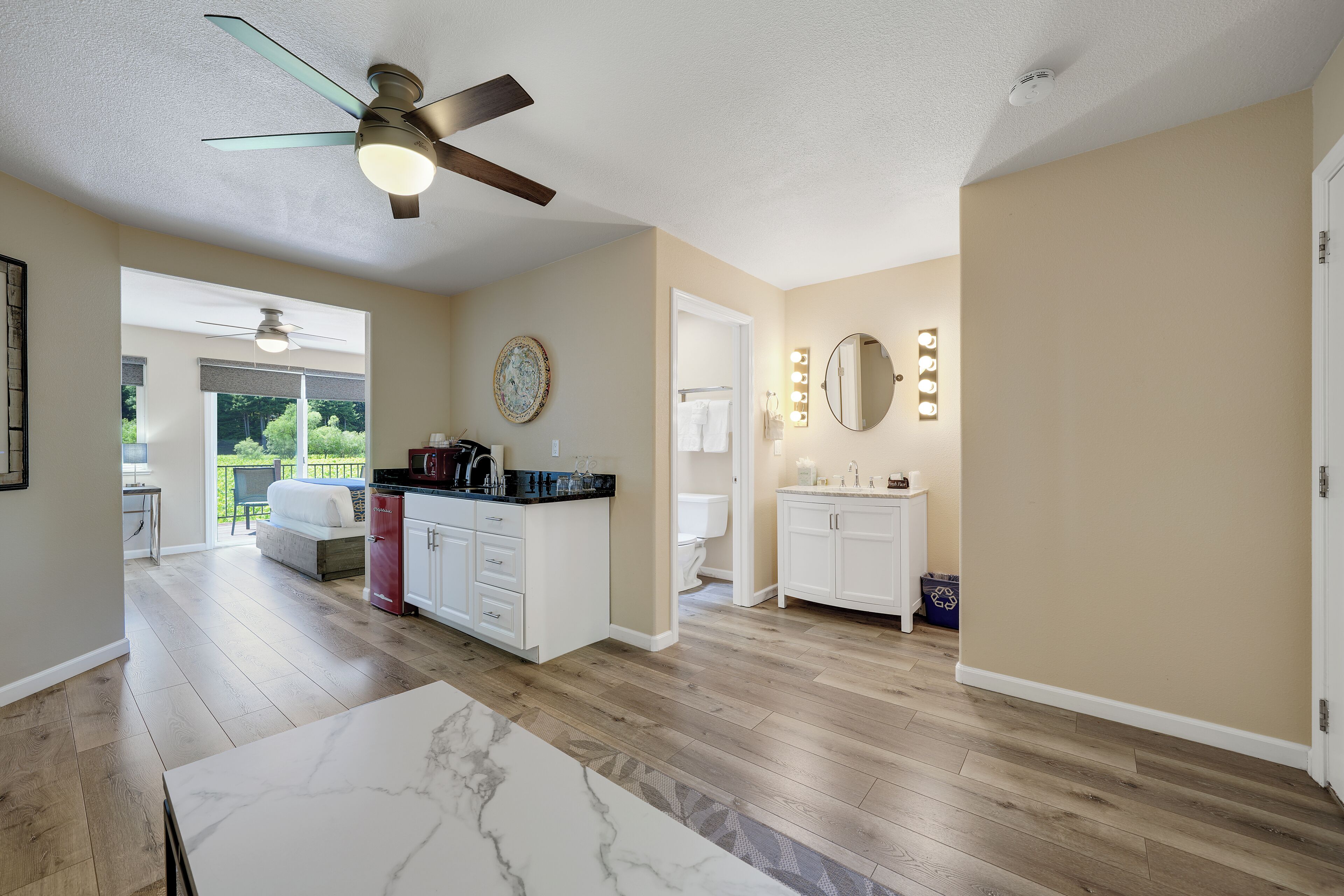 A spacious living area with a ceiling fan, a dining table, and a view of the outdoors.