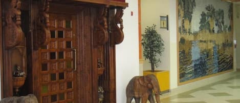 An entrance with a sign reading "India Palace," a wooden door with intricate carvings, and a mural depicting a landscape.
