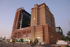 Een meerlaags gebouw met een opvallende ingang en borden met 'Mazyad Mall' en 'Al Arabiya Hotel Apartment'.