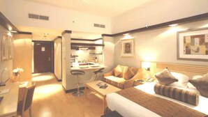 Een hotelkamer met een bed, een slaapbank, een bureau en een kitchenette.