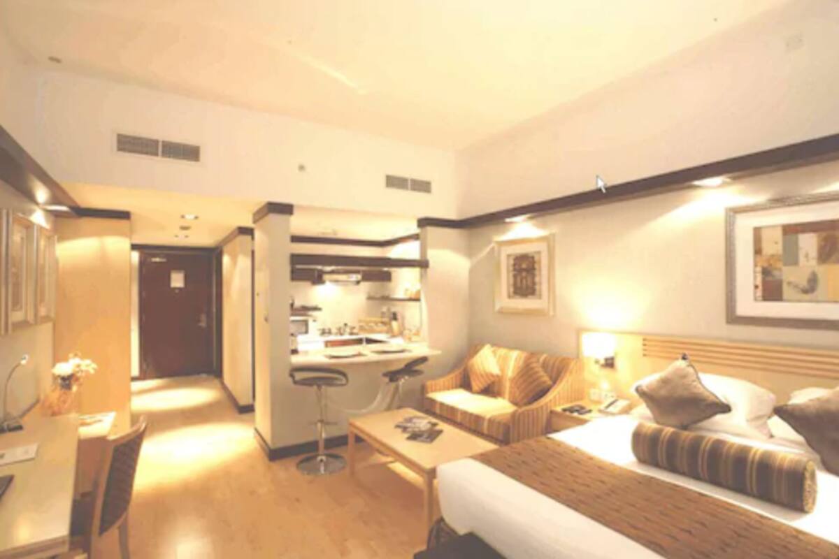 Een hotelkamer met een bed, een slaapbank, een bureau en een kitchenette.