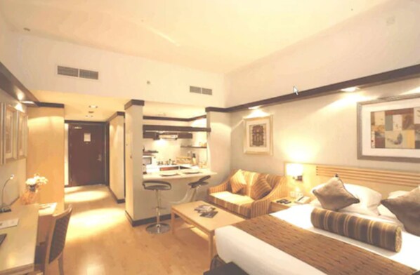 Een hotelkamer met een bed, een slaapbank, een bureau en een kitchenette.