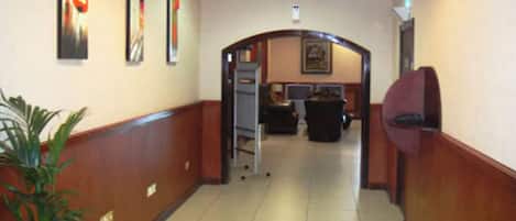 Un pasillo de hotel con mostrador de recepción, zona de estar y un basurero.
