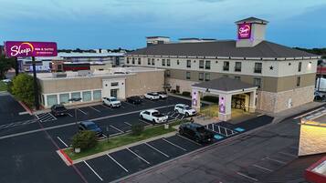 Un hotel Sleep Inn & Suites con estacionamiento, varias construcciones y cielo despejado.