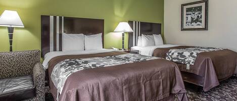 A hotel room with two beds, a sofa, and a patterned rug.