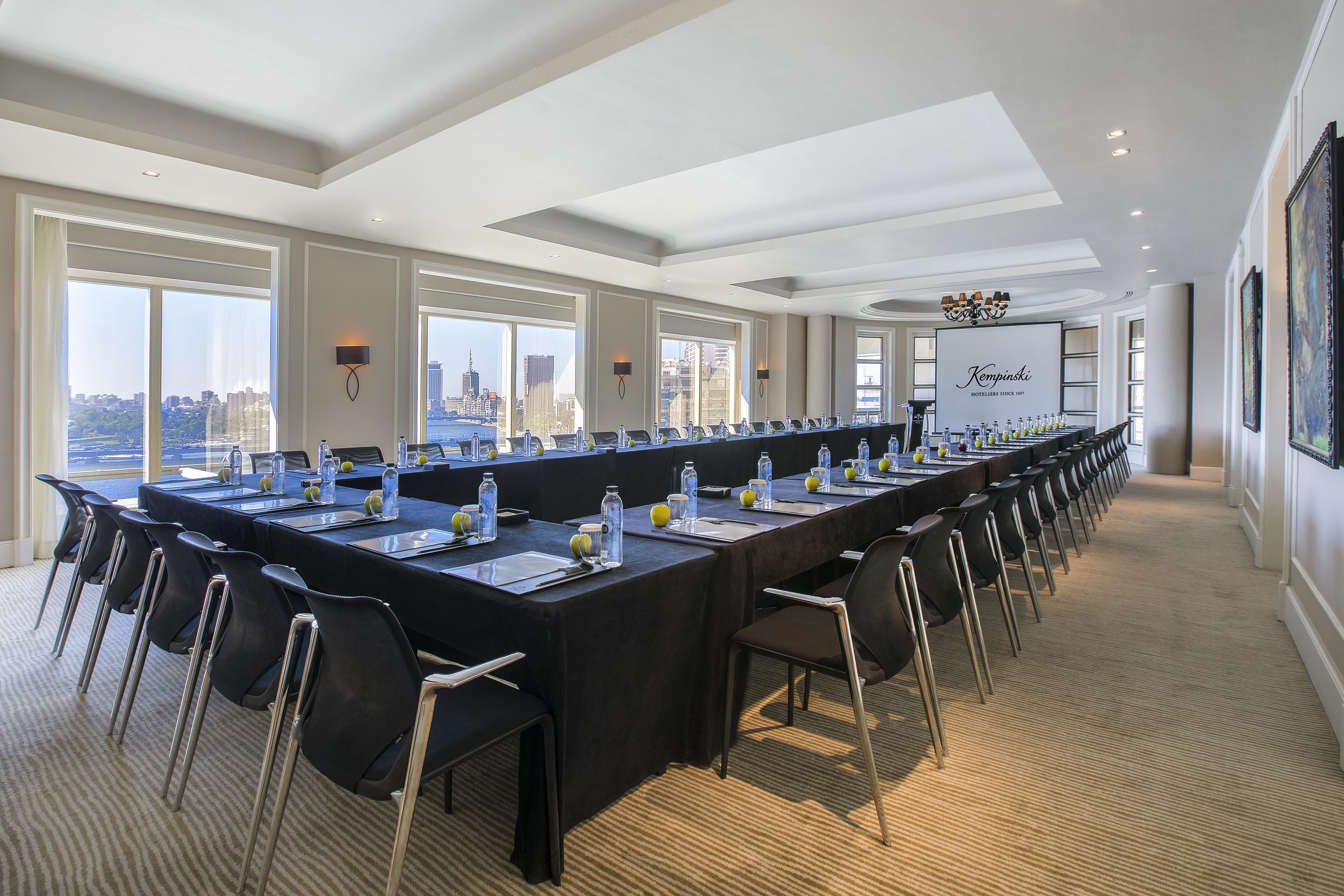 A conference room with a long table, chairs, and city views through large windows.