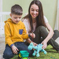 A child playing with a toy truck and a giraffe on a green carpet.
