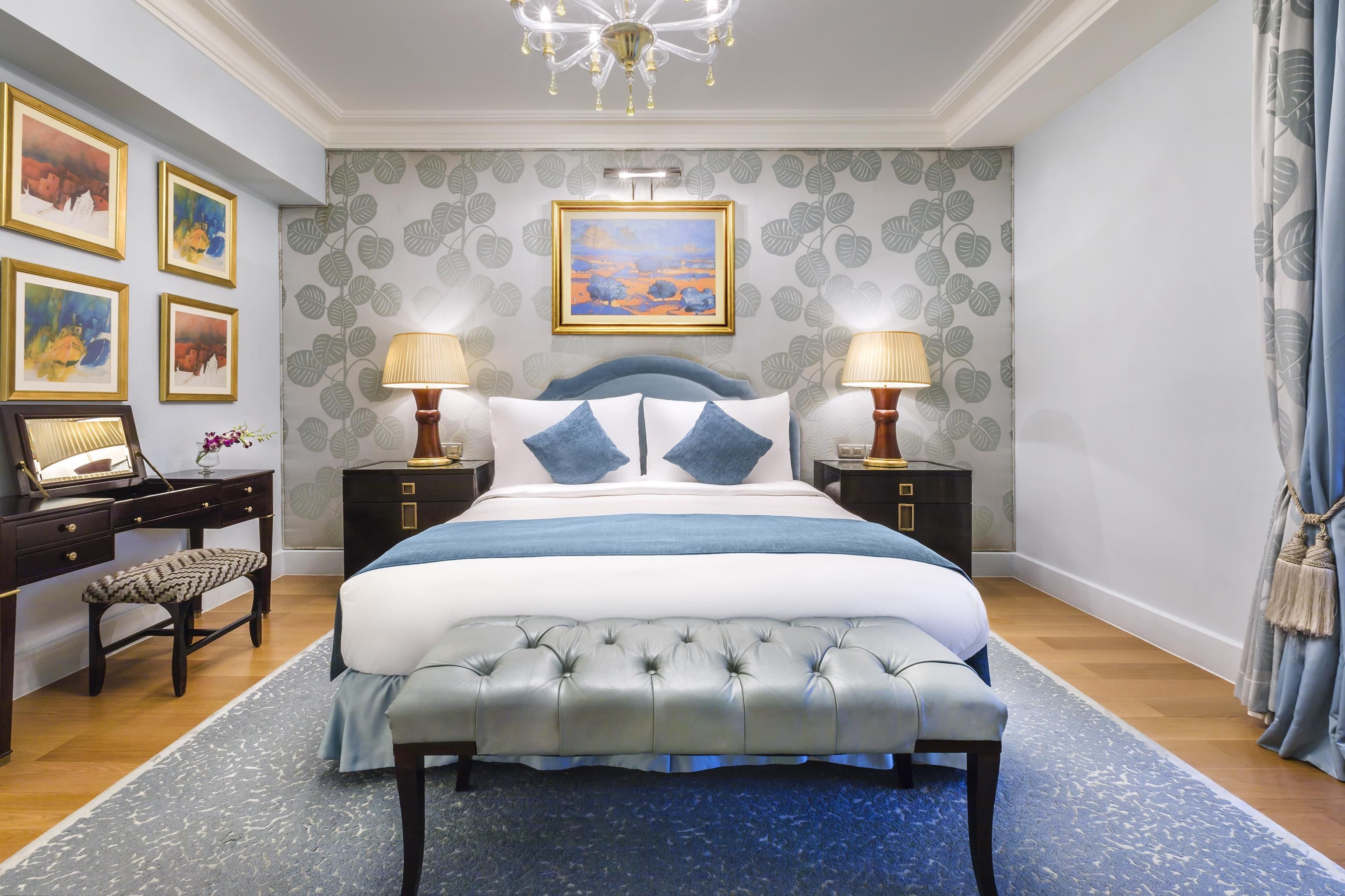 A bedroom with a large bed, two bedside tables, a desk, and a chair.