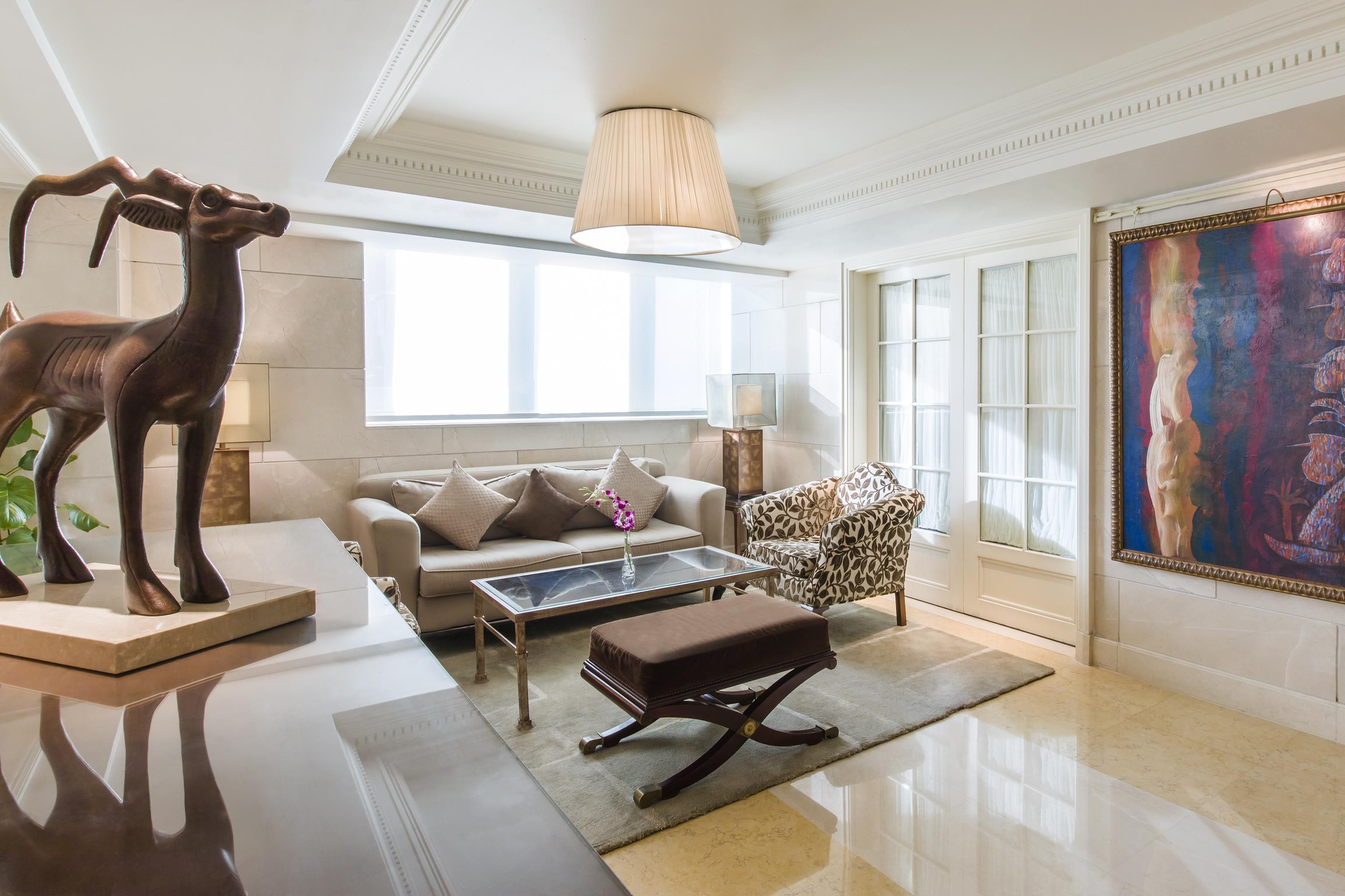 A modern living room with a sofa, coffee table, ottoman, and a decorative sculpture.