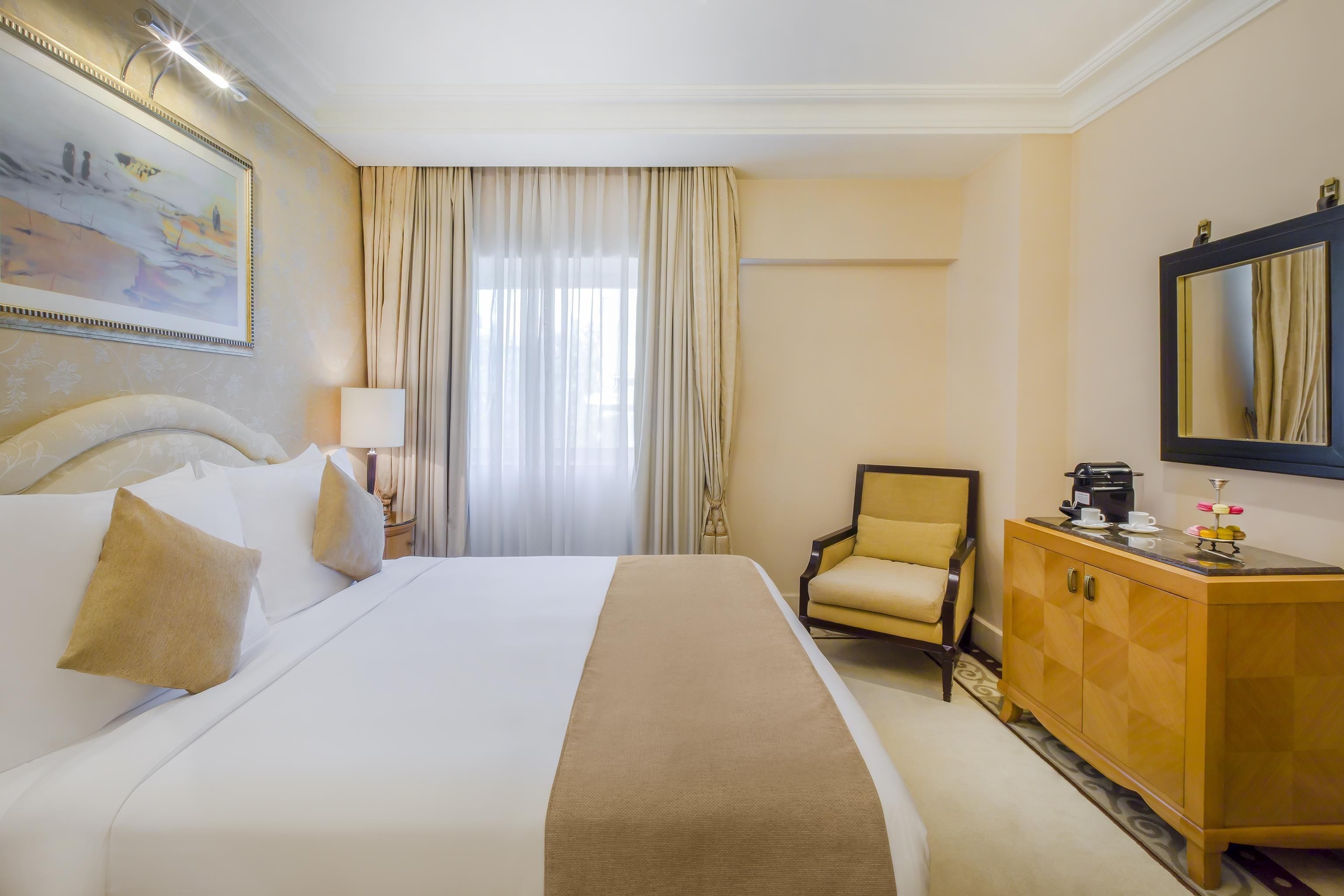 Una habitación de hotel con una cama grande, una silla, un escritorio y un espejo.