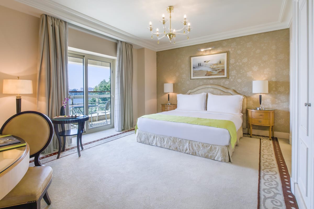 Camera d'albergo con un letto grande, due comodini, un lampadario, un quadro appeso alla parete e vista attraverso una grande finestra.