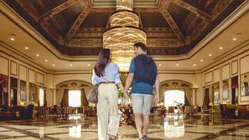 A spacious lobby with a grand chandelier, marble flooring, and classical architecture.