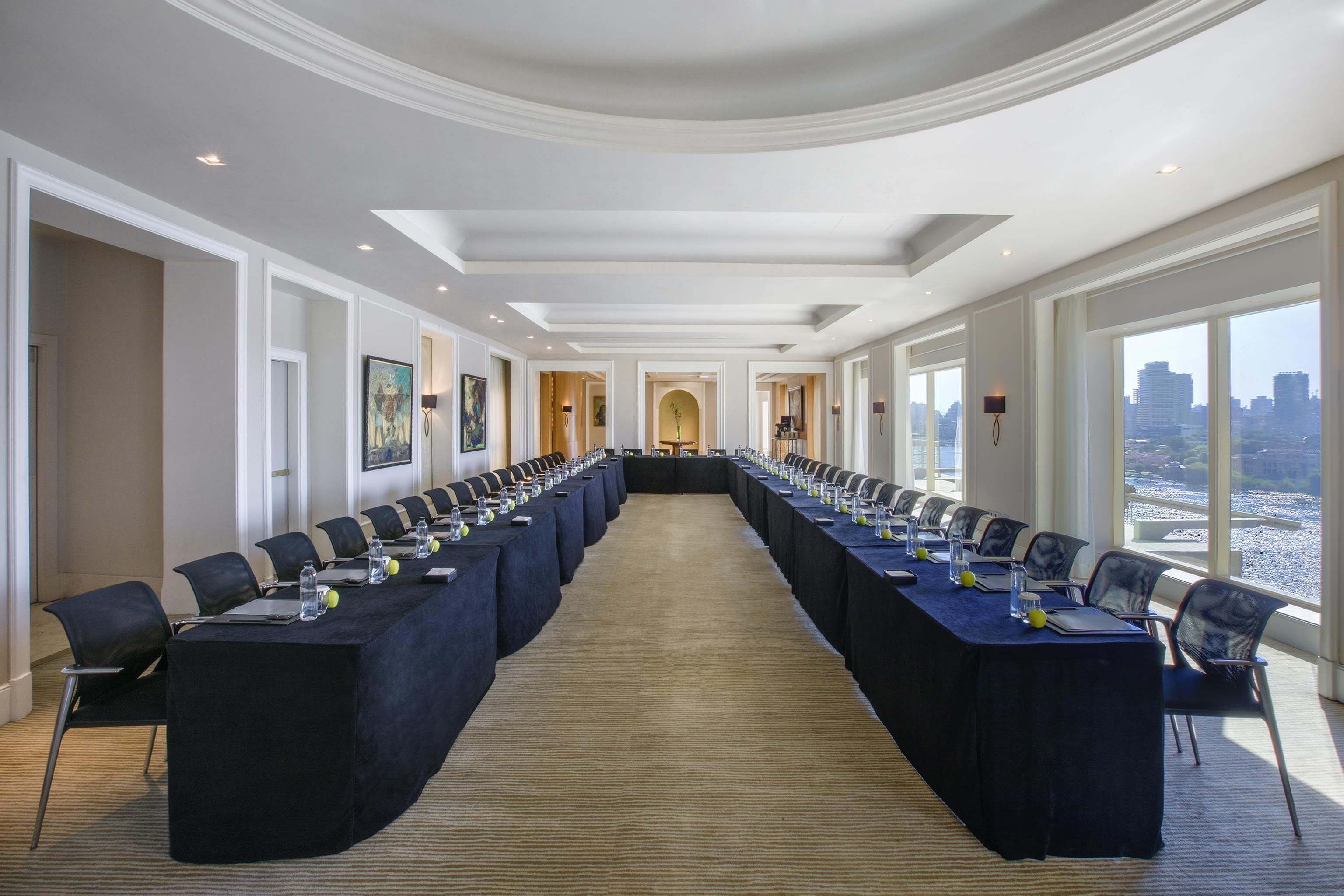 A conference room with a long table, chairs, and a carpeted floor.