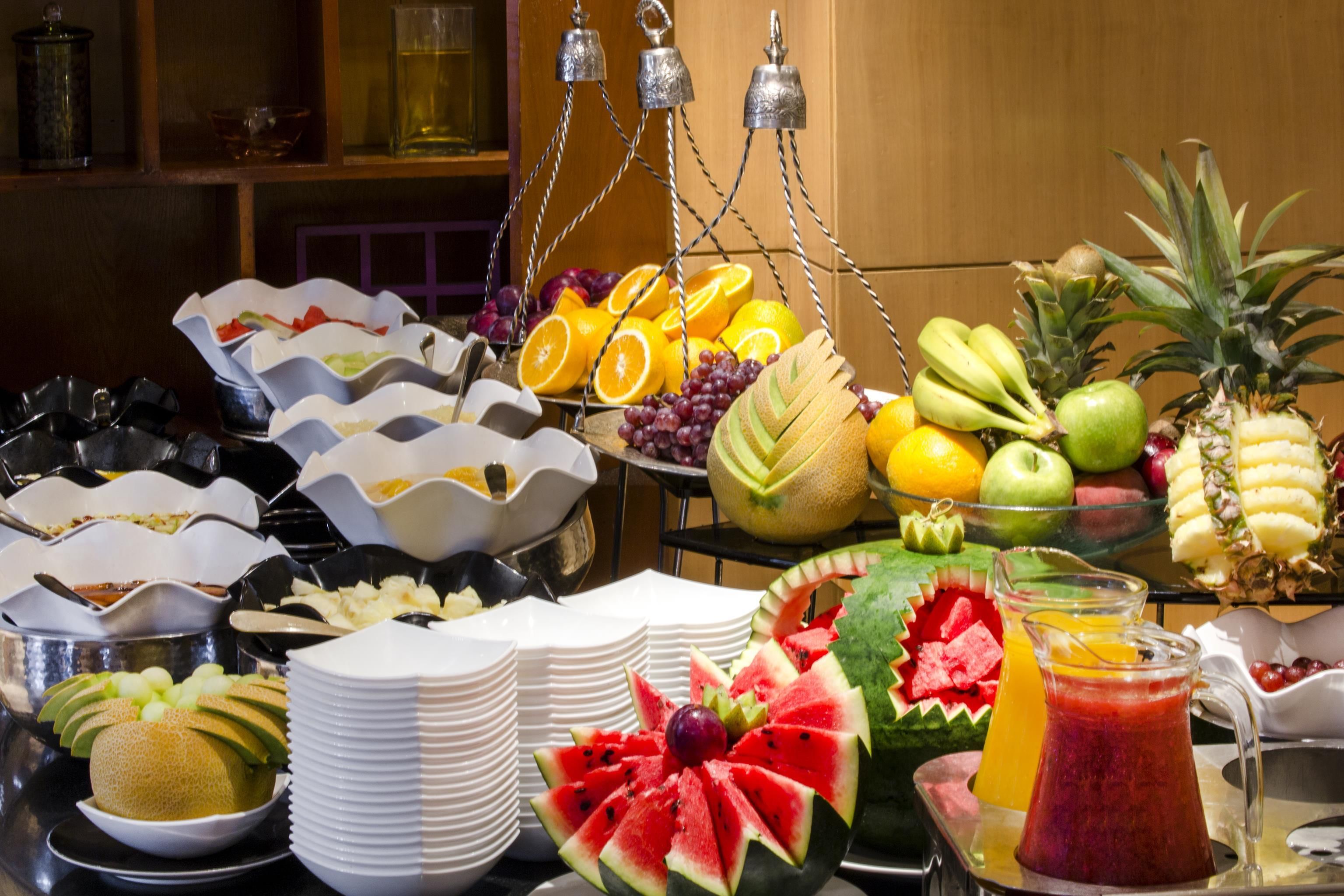 A buffet with various fruits, vegetables, and beverages.