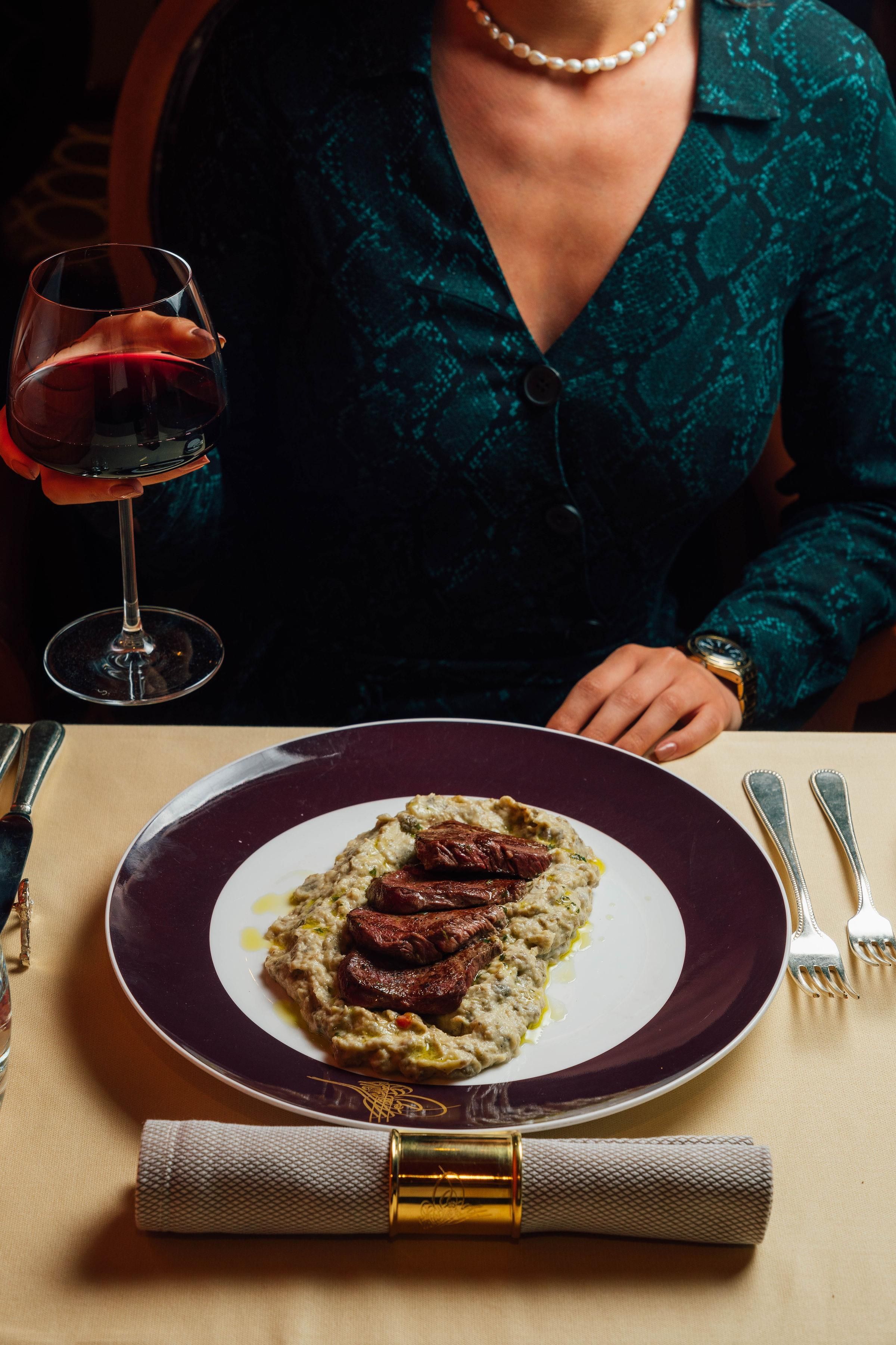 A dining table with a plate of food, a wine glass, and cutlery.