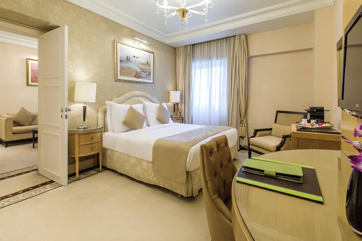 Una camera d'albergo con un letto grande, una scrivania, una sedia, una televisione e un quadro appeso al muro.