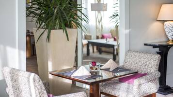 Un comedor moderno con una mesa de vidrio, sillas estampadas, una planta en maceta y una lámpara.