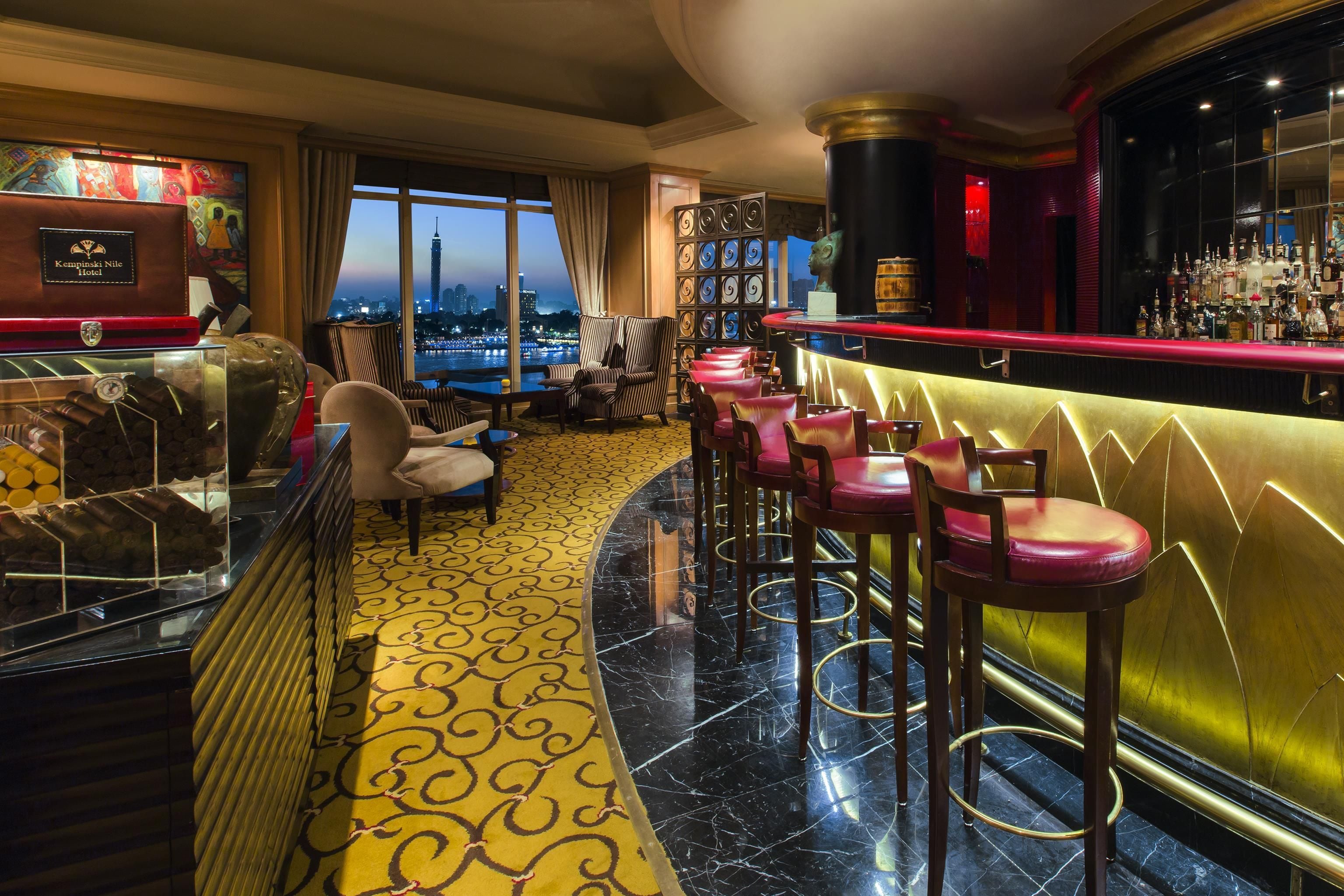 A bar area with a city view, bar stools, and a patterned floor.