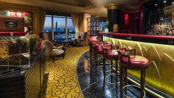 A bar area with a city view, bar stools, and a patterned floor.