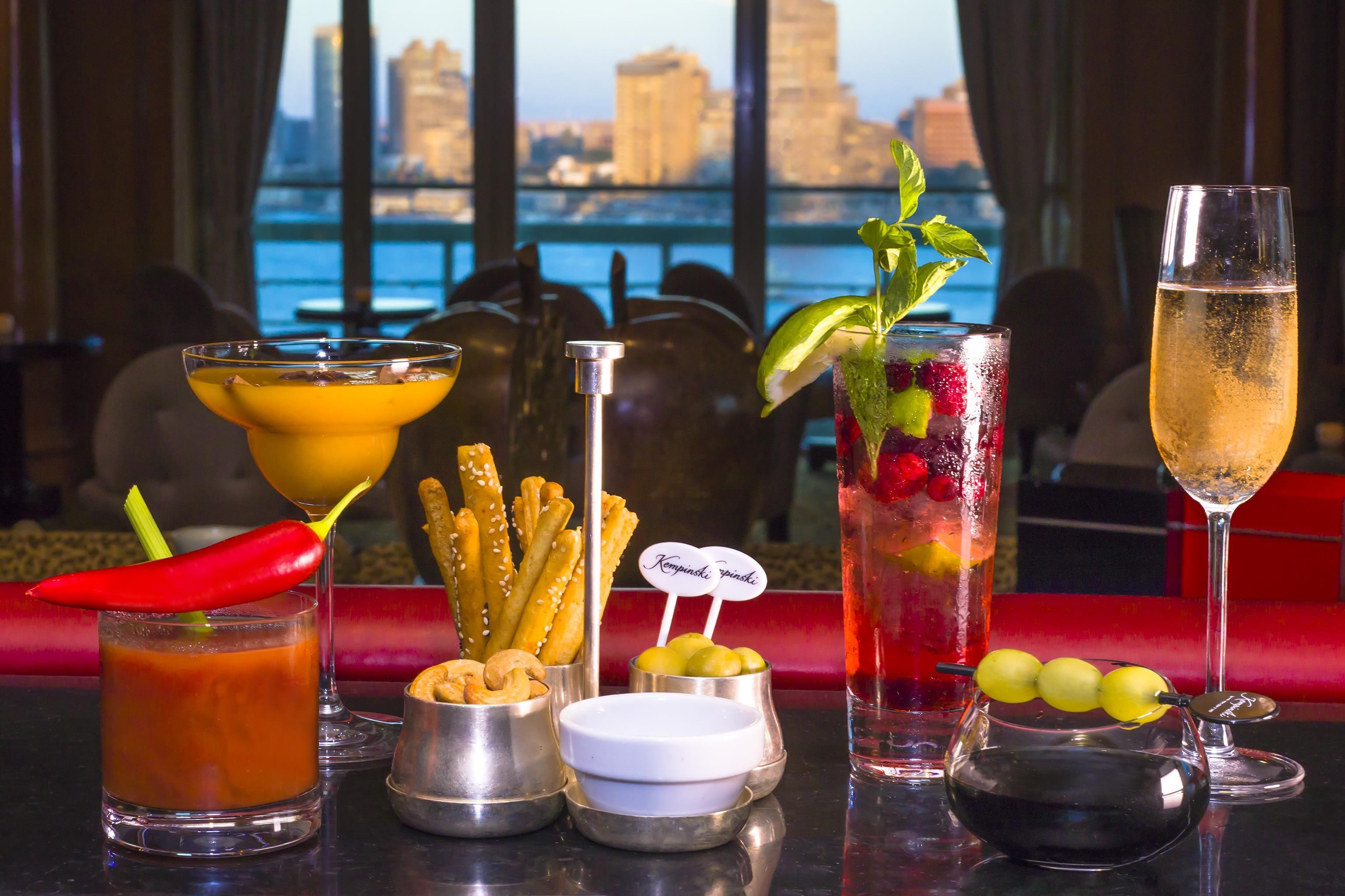 A bar setting with various drinks, snacks, and a city view.