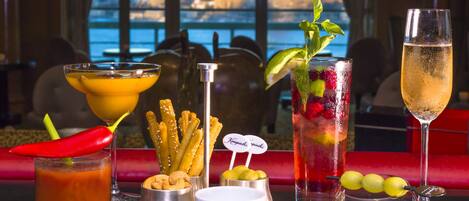 A bar setting with various drinks, snacks, and a city view.