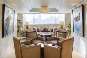 A modern living room with a sofa, armchairs, a coffee table, and artwork on the walls.