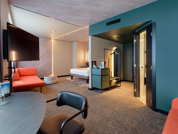 Une chambre d’hôtel équipée d’un lit, d’un bureau, d’une chaise, d’une télévision et d’un mini-bar.