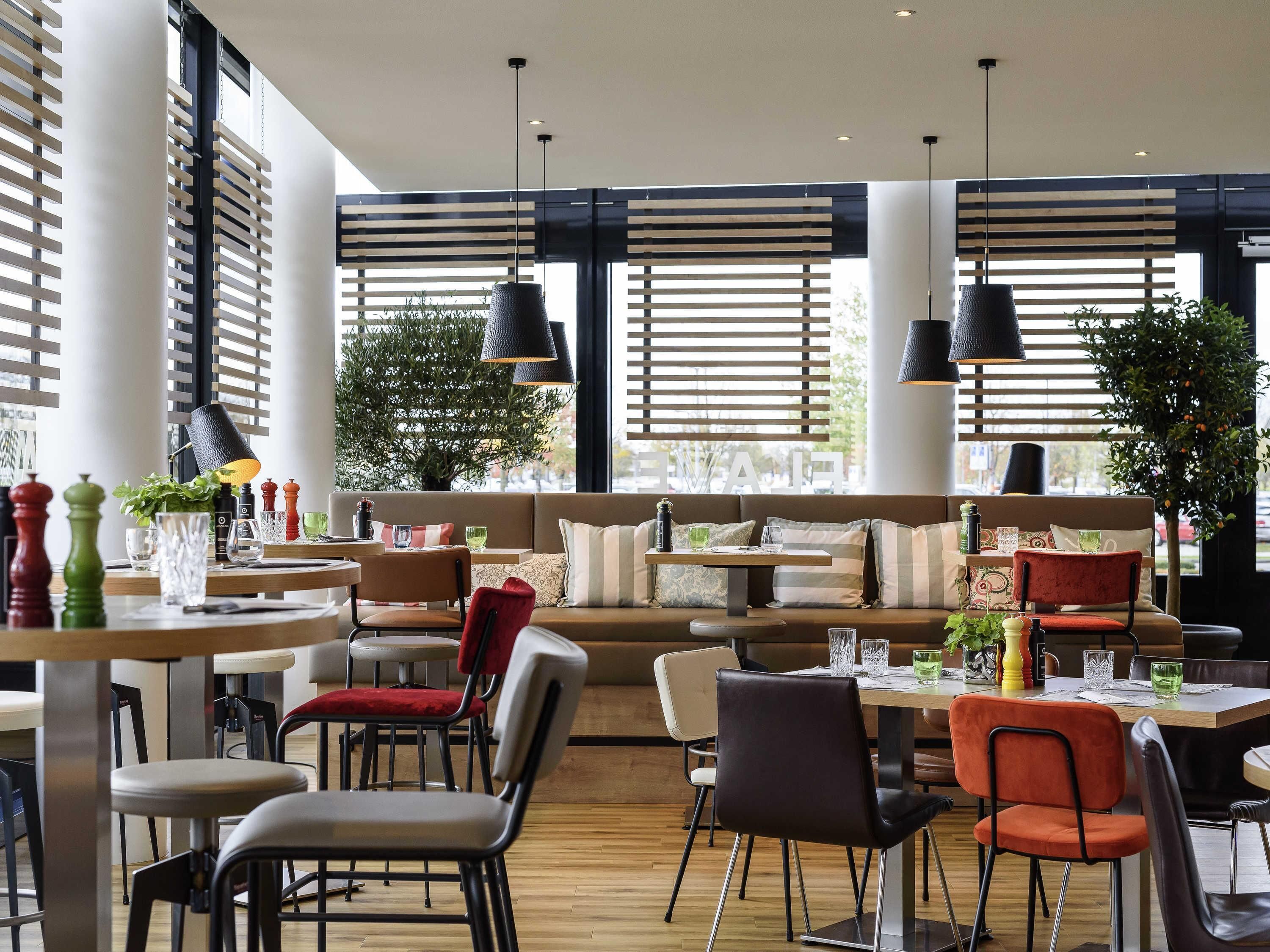 Un intérieur moderne comprenant un espace salon, des tables et des luminaires suspendus.