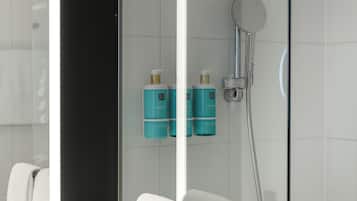 Ein modernes Badezimmer mit Duschkabine aus Glas, weißen Fliesen und zwei Shampooflaschen an der Wand.