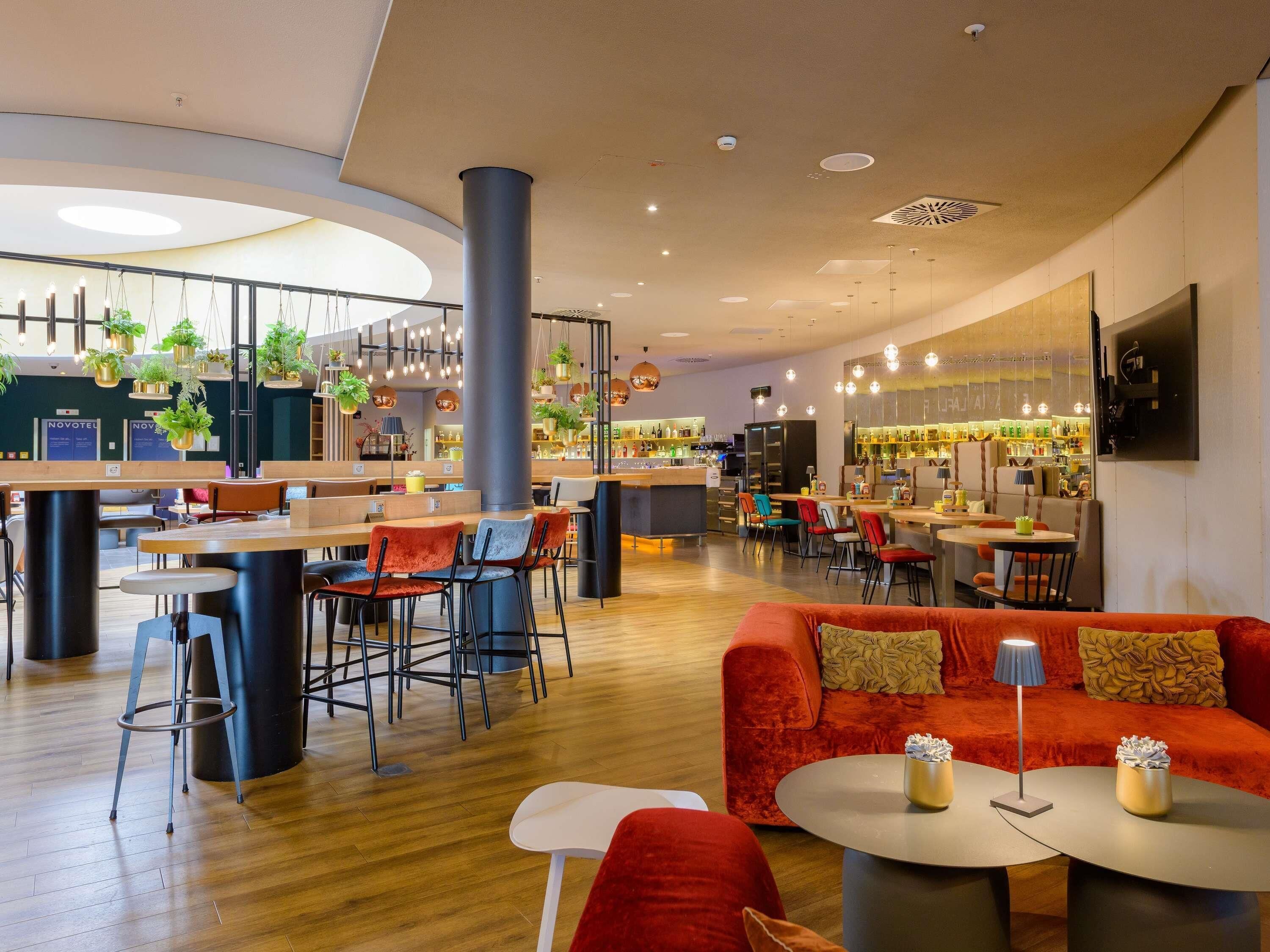 Un interior moderno con una zona de bar, arreglos de asientos y una columna central.