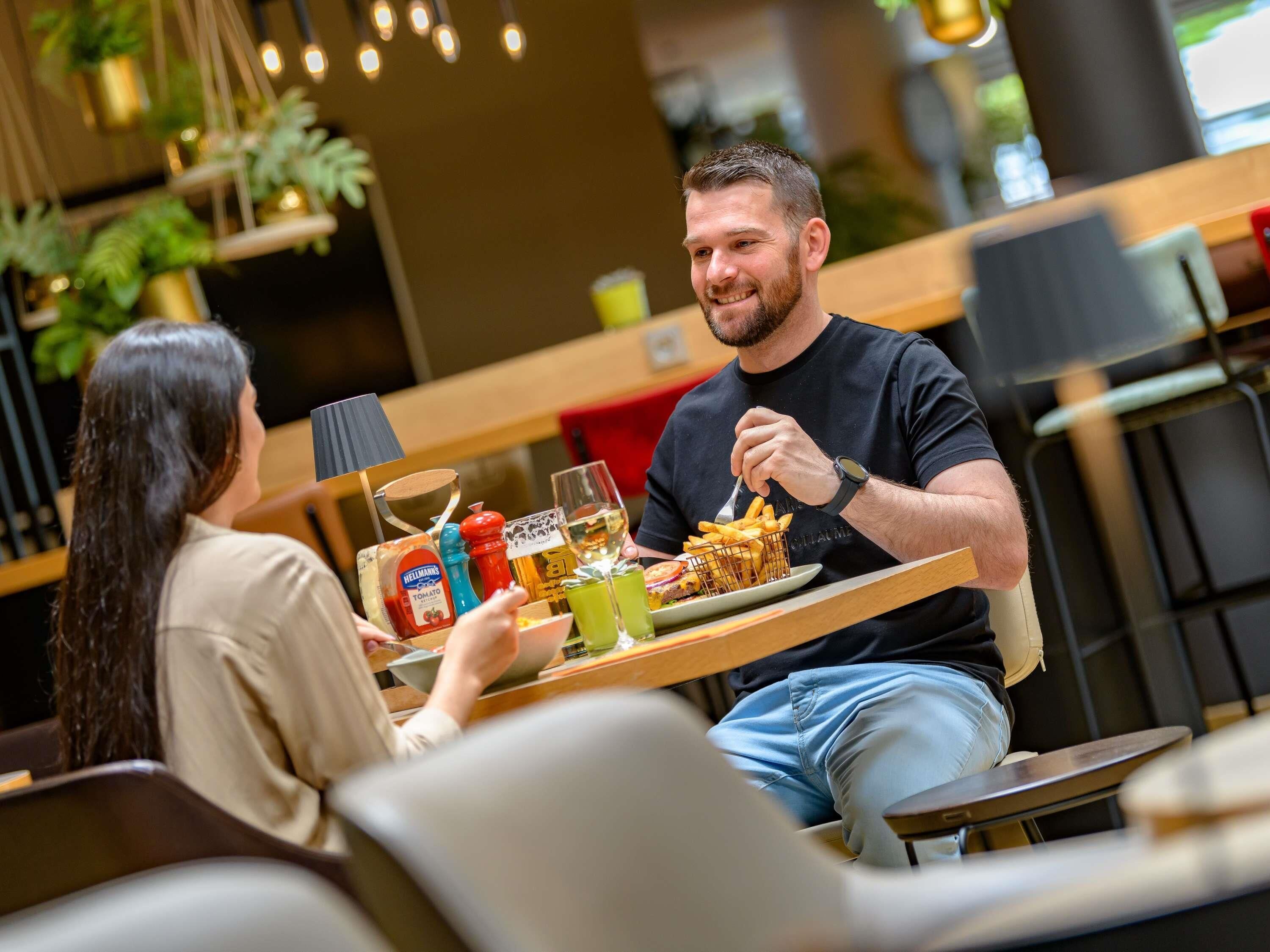 A couple dining at a restaurant with a variety of condiments and drinks on the table.