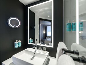 Un baño moderno con un espejo grande, un lavabo blanco y una zona de ducha.