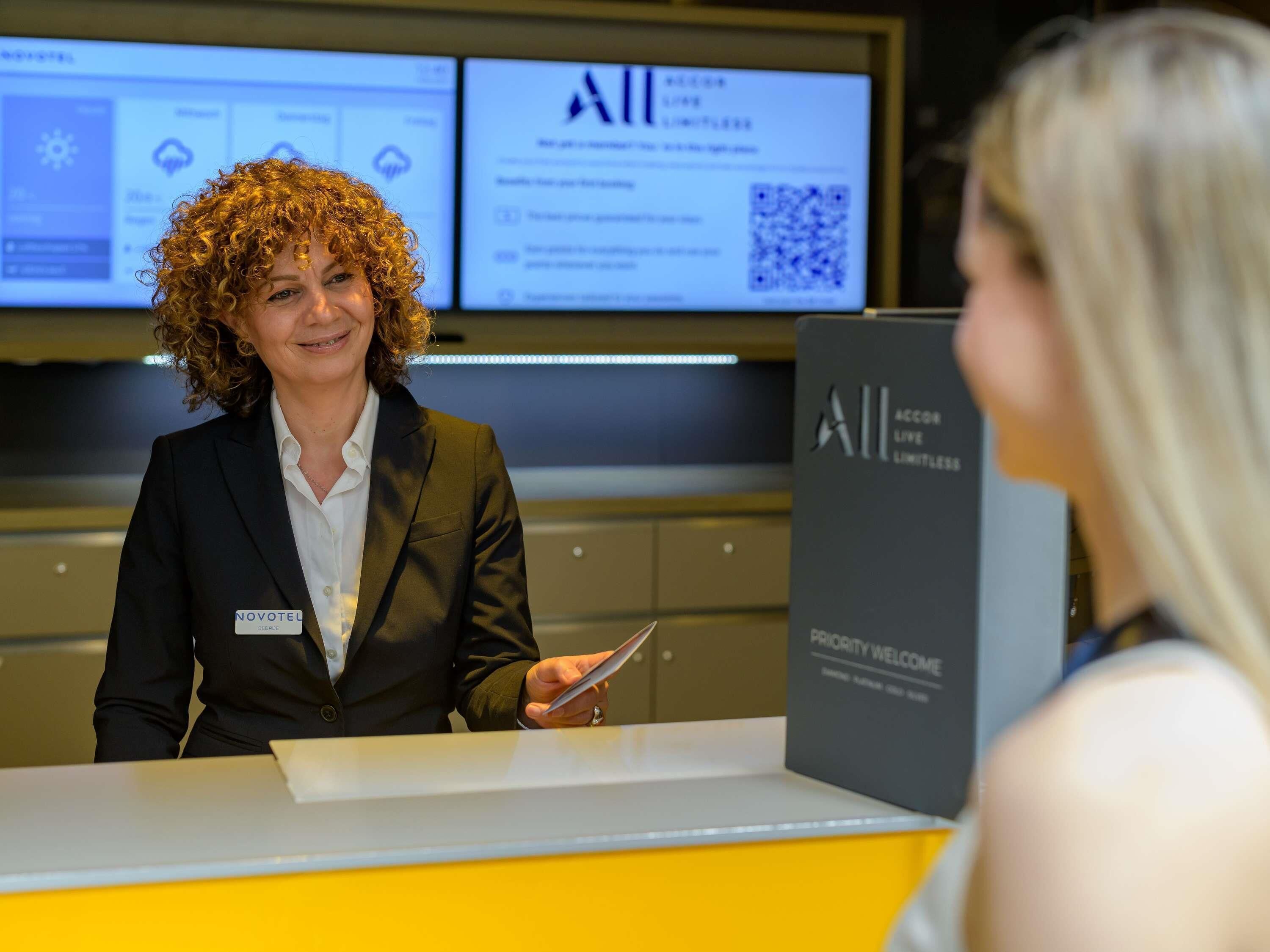 A reception desk with a name tag, a digital display, and a sign reading 'Priority Welcome.'