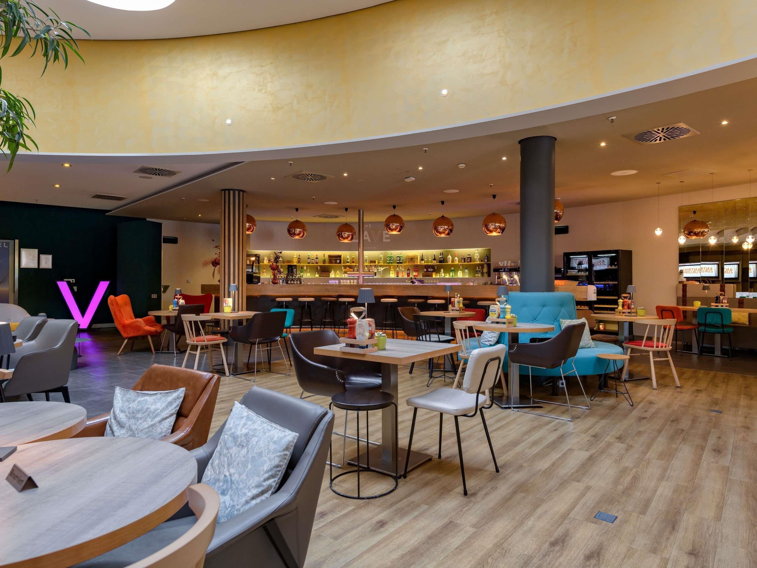 A modern hotel lobby with a bar area, seating arrangements, and a large 'V' sign.