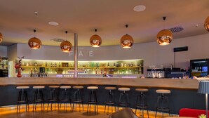 A bar area with a counter, stools, and a barista station. - Novotel München Airport (Freising)