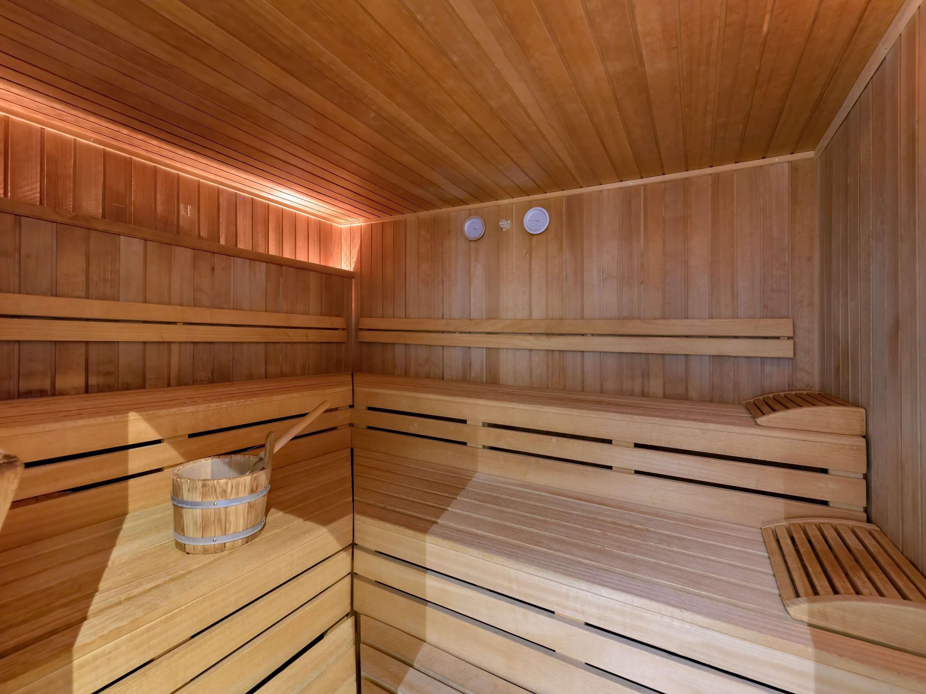A sauna with wooden benches and a wooden bucket.