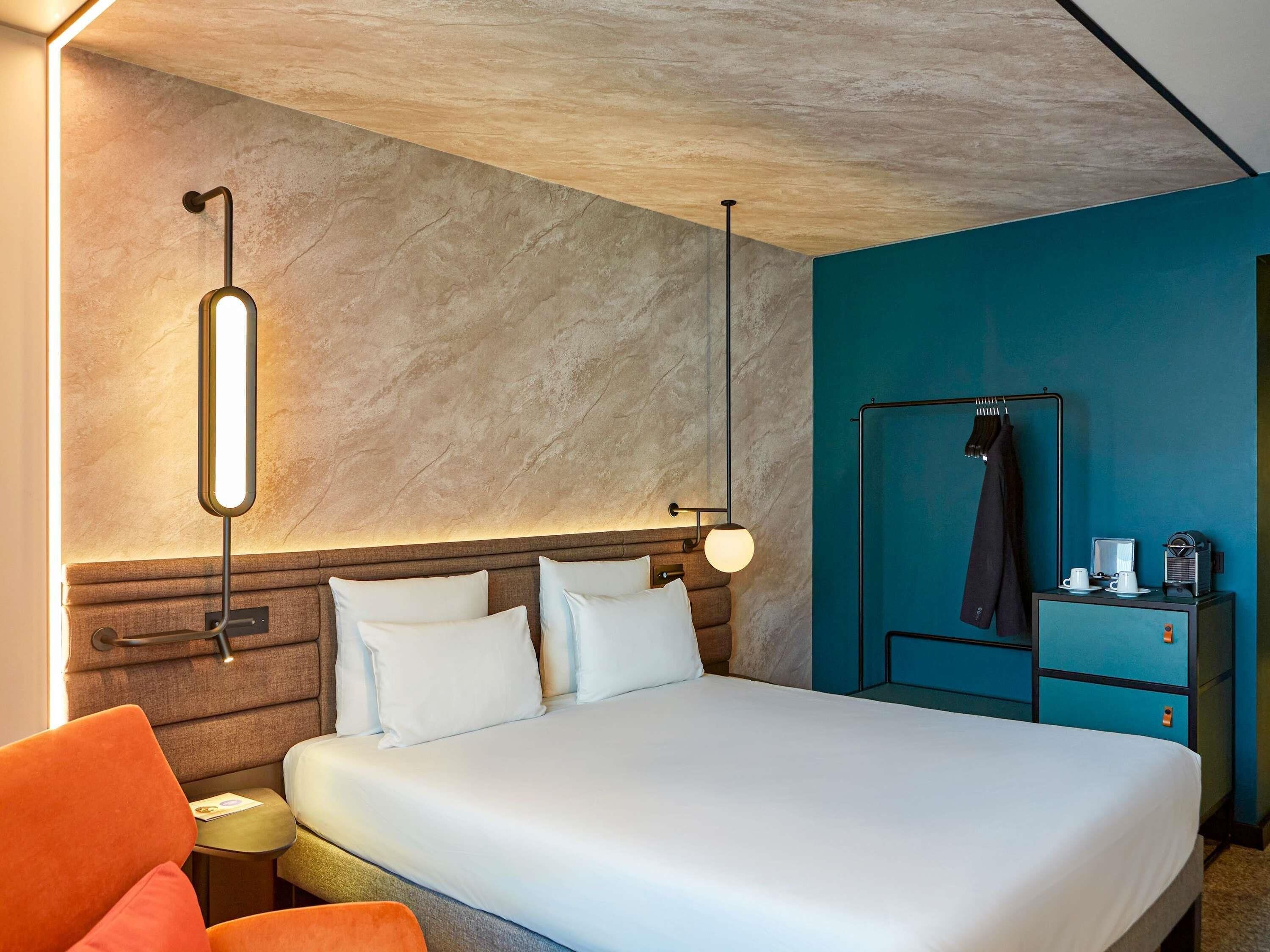 Een moderne hotelkamer met een groot bed, een nachtkastje, een bureau met stoel en een kledingkast.