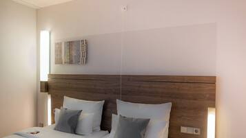 Een moderne hotelkamer met een houten hoofdeinde, een flatscreen televisie aan de muur en een nachtkastje met een lamp.
