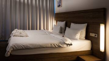 A neatly made bed with white linens, a wooden headboard, and a bedside table with a lamp.