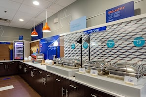 A breakfast buffet area with labeled food stations, a cereal refrigerator, and directional signs. - Holiday Inn Express Atlanta Airport West - Camp Creek Market by IHG (Atlanta)