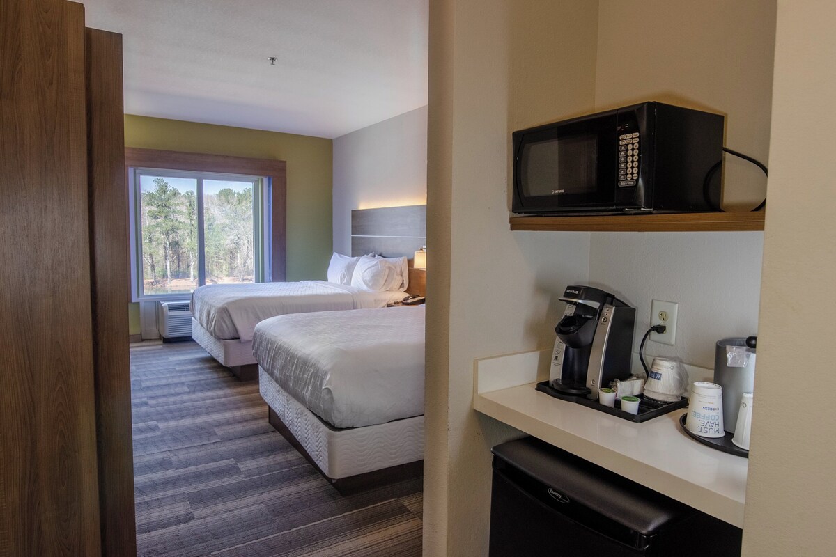 Quarto de hotel com duas camas, micro-ondas, cafeteira e pequeno frigorífico.