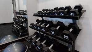 A gym with multiple rows of black dumbbells on a rack, a mirror reflecting the gym equipment, and exercise balls on the floor. - Holiday Inn Express Atlanta Airport West - Camp Creek Market by IHG (Atlanta)