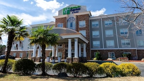 A Holiday Inn Express & Suites building with a brick facade, large windows, and a covered entrance area. - Holiday Inn Express Atlanta Airport West - Camp Creek Market by IHG (Atlanta)