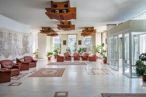 A spacious lobby with leather sofas, a patterned rug, and a large wall mural. - Traian Braila (Braila)