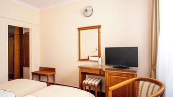 A hotel room with two beds, a desk with a television, a chair, and a mirror.