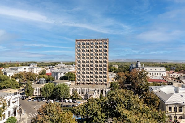 A tall building with a grid-like facade, surrounded by other buildings and trees. - Traian Braila (Braila)