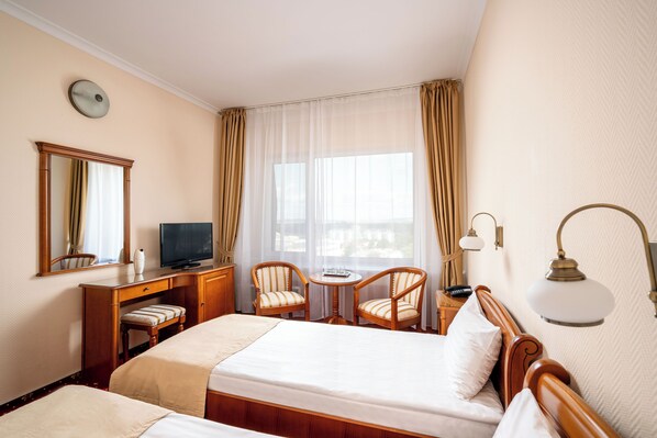 A hotel room with a bed, a desk, a television, two chairs, a lamp, and a window with curtains. - Traian Braila (Braila)