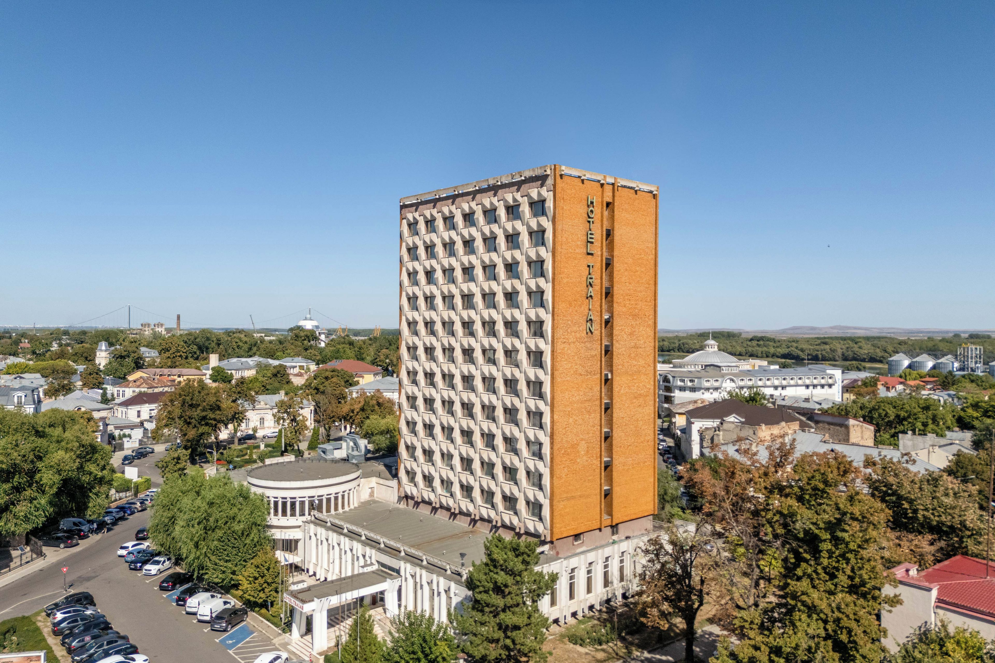 Un hotel alto con una fachada de diseño característico en forma de cuadrícula, rodeado de edificios residenciales y comerciales.