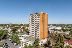 Un hotel alto con una fachada de diseño característico en forma de cuadrícula, rodeado de edificios residenciales y comerciales.