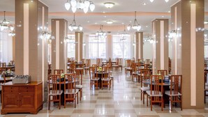 A spacious dining area with multiple tables and chairs, large windows, and decorative chandeliers. - Traian Braila (Braila)